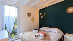 Ein Schlafzimmer mit einem Bett, Kissen, einem Nachttisch und einem Fenster mit Vorhängen.