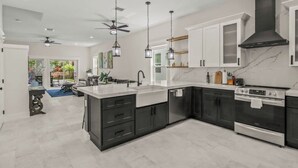 A modern kitchen with dark cabinetry, a marble countertop, and stainless steel appliances. - Welcome to Casa Rio, our spacious house in scenic Jensen Beach! (Jensen Beach)
