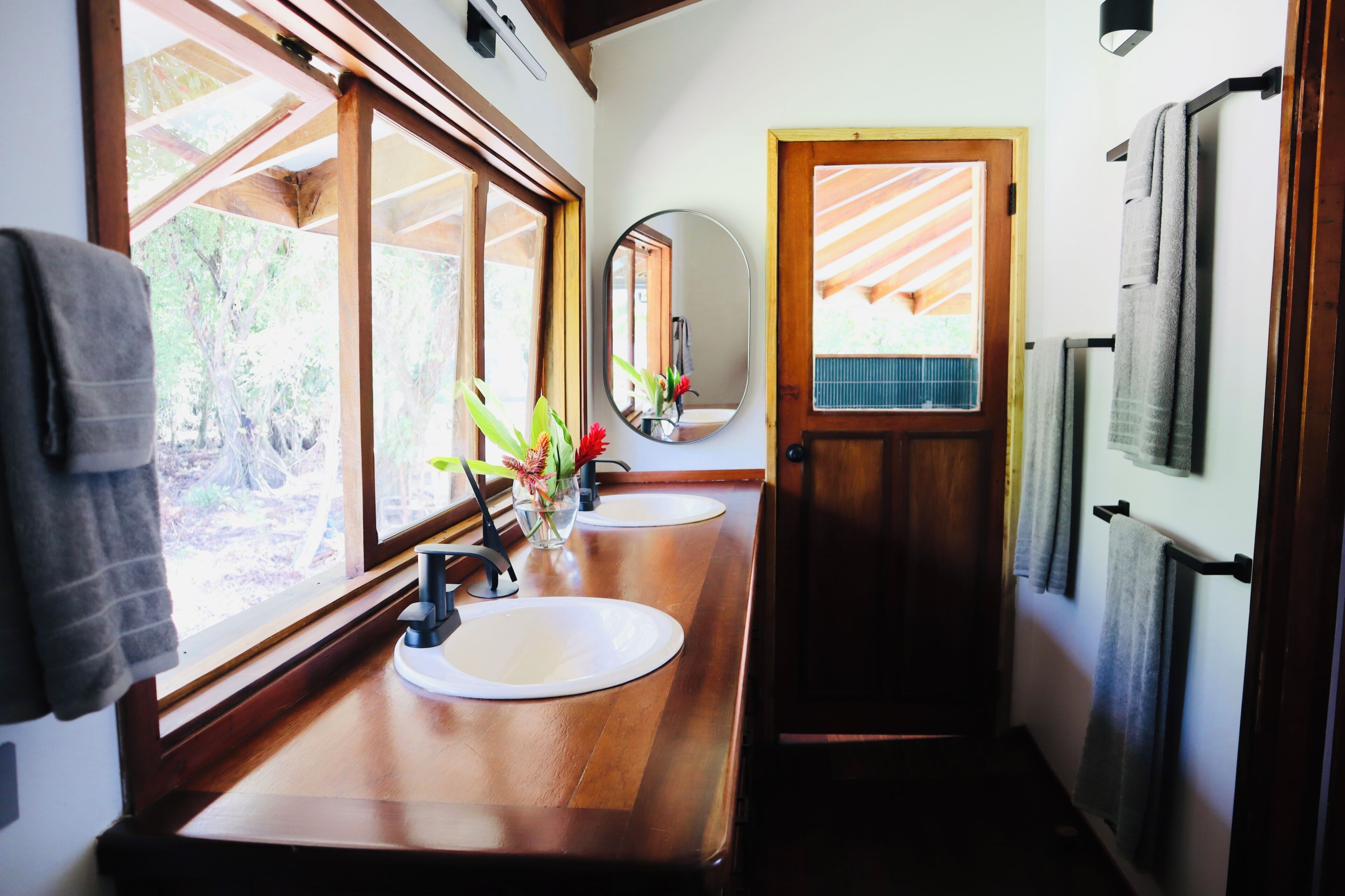 A bathroom with wooden countertops, two sinks, a mirror, and towels hanging on a rack.