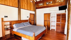 A wooden-framed bedroom with a bed, bedside tables, a wardrobe, and a ceiling fan.