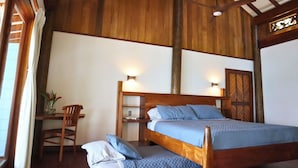 A wooden-framed bedroom with a bed, bedside tables, and a chair.