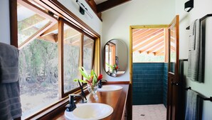 A bathroom with two sinks, a mirror, and a view of the outdoors.