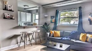Un salon moderne avec un canapé gris, une table basse et un coin repas agrémenté d’une chaise blanche.