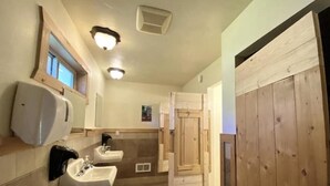 Un baño con dos lavamanos, un secador de manos y una puerta de madera.