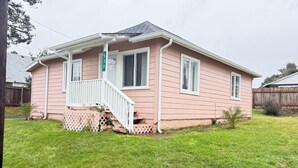 A single-story house with a front porch, a small front yard, and a wooden fence in the background.