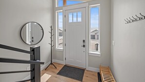 A modern entryway with a white door, a coat rack, and a small bench.