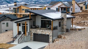 A modern two-story house with a stone facade, a large garage, and a balcony.