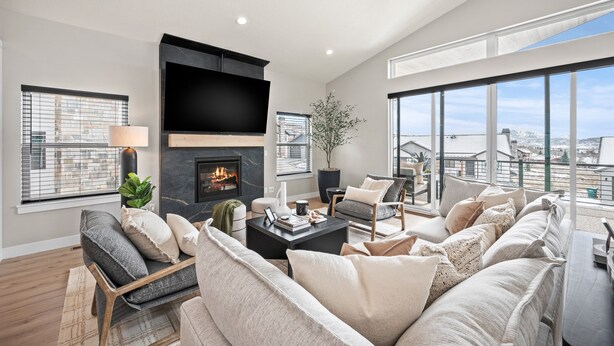 A modern living room with a fireplace, large windows, and a view of the city.