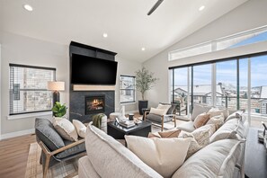 A modern living room with a fireplace, large windows, and a view of the city. - Powder Heaven B8 | Powder Mtn Ski Lodge | Hot Tub (Eden)