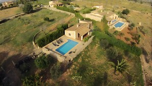 A villa with a swimming pool, surrounded by greenery and hills.