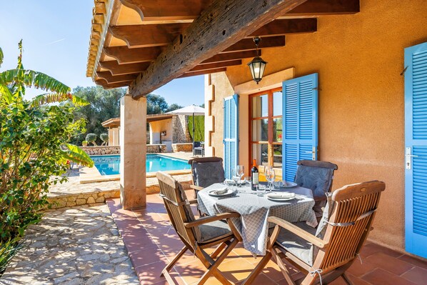 A patio with a table set for dining, a pool, and a stone pathway.