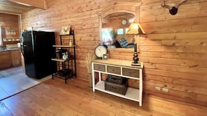 A wooden interior with a wooden-framed console table, a clock, and a mounted animal head.