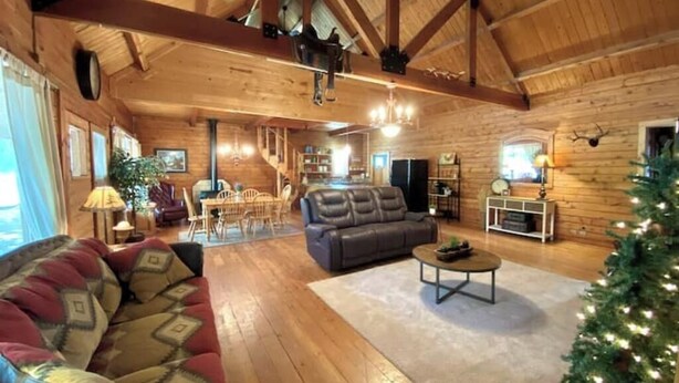 A spacious living room with a wooden ceiling, a sofa, a coffee table, and a Christmas tree.