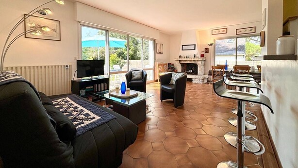 Una sala de estar amplia con chimenea, televisor y un comedor con taburetes de bar.