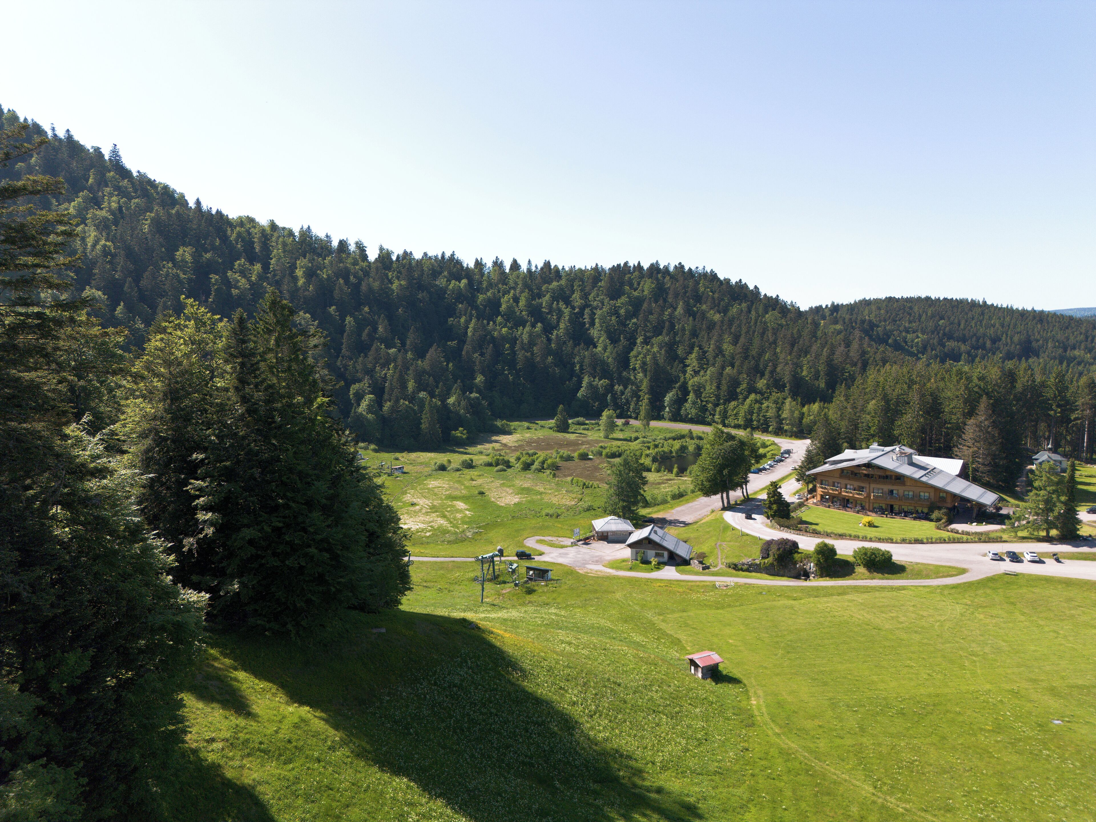A lodge with a large building and a smaller structure, surrounded by a lush green landscape and dense forest.