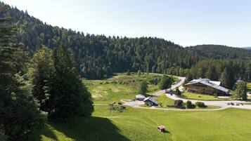 A lodge with a large building and a smaller structure, surrounded by a lush green landscape and dense forest.