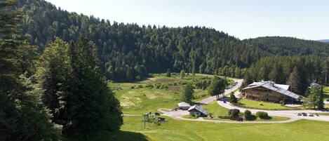 A lodge with a large building and a smaller structure, surrounded by a lush green landscape and dense forest.