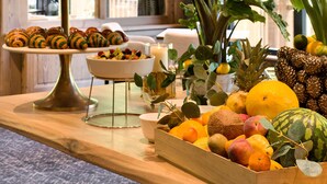 A buffet table with pastries, fruits, and a decorative plant arrangement. - Domaine de Montagne  Chalet Frère Joseph (Ventron)