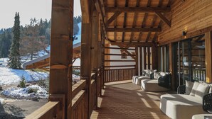 A wooden deck with outdoor seating and a view of a snowy landscape. - Domaine de Montagne  Chalet Frère Joseph (Ventron)