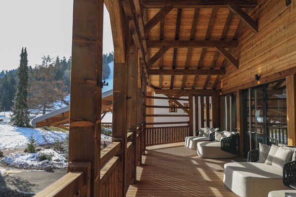 Una terraza de madera con mobiliario exterior y vistas a un paisaje nevado.