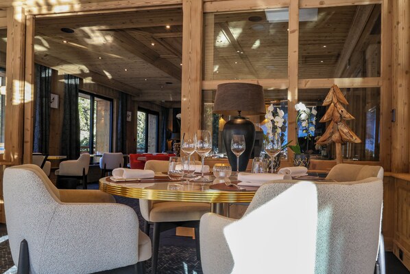 A dining area with a round table set for four, surrounded by upholstered chairs. - Domaine de Montagne Chalet Frère Joseph (Ventron)