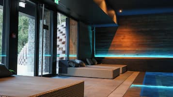 Relax in a comfortable seating area with a patterned bench and cushions, surrounded by a dynamic illuminated wall and a clear glass door leading to an outdoor space.