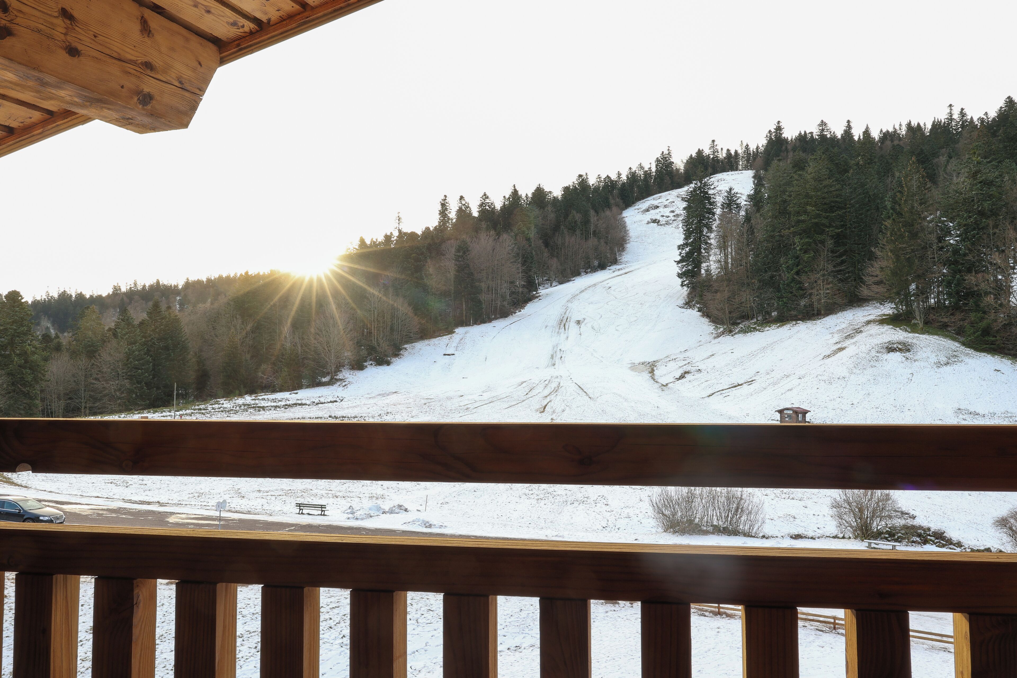 A snowy mountain landscape with a wooden deck and a bench.