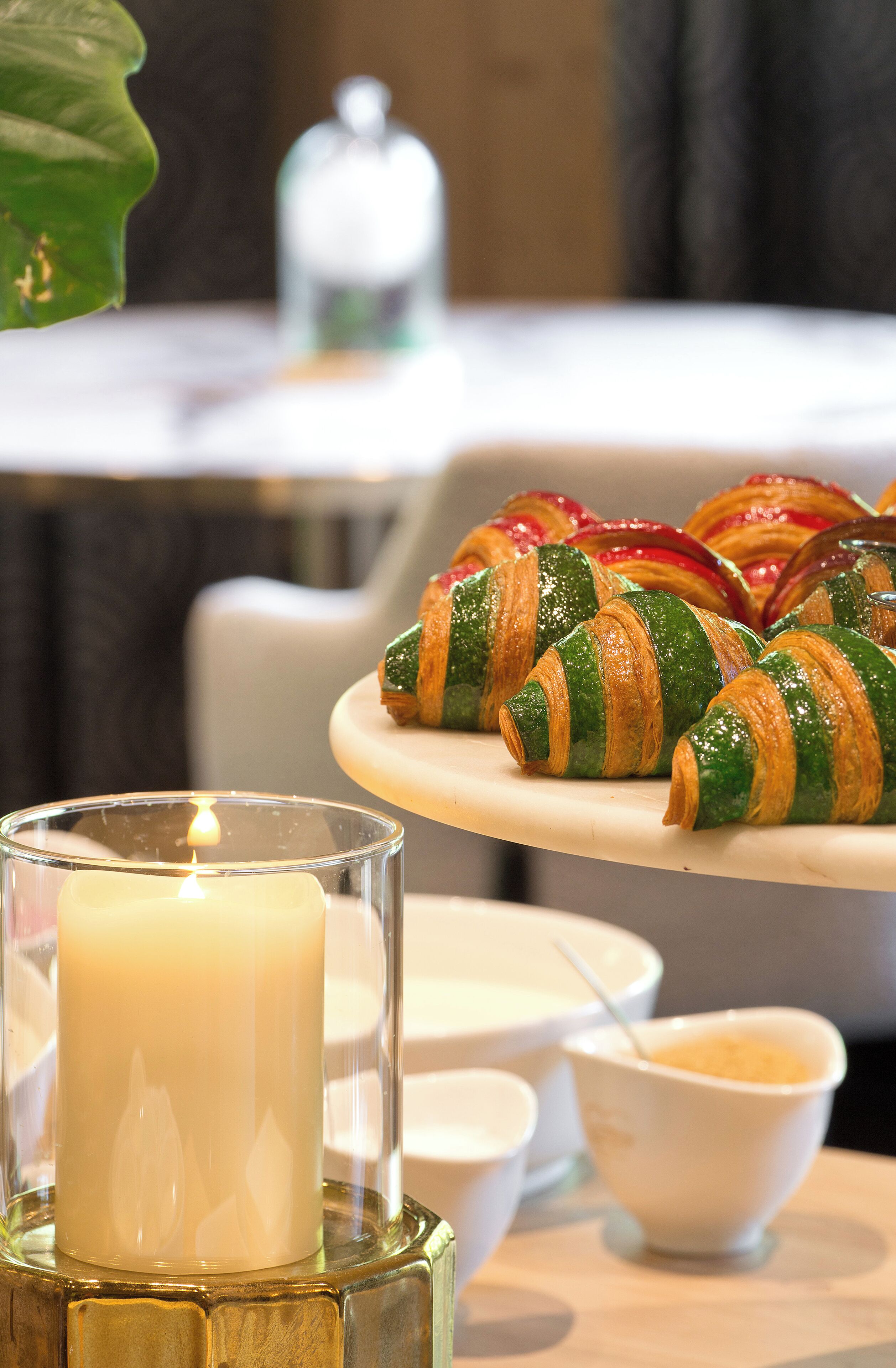 A table with croissants and a lit candle.