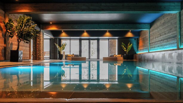 A modern indoor pool area with a clear view of the pool, wooden walls, and seating areas. - Domaine de Montagne  Chalet Frère Joseph (Ventron)