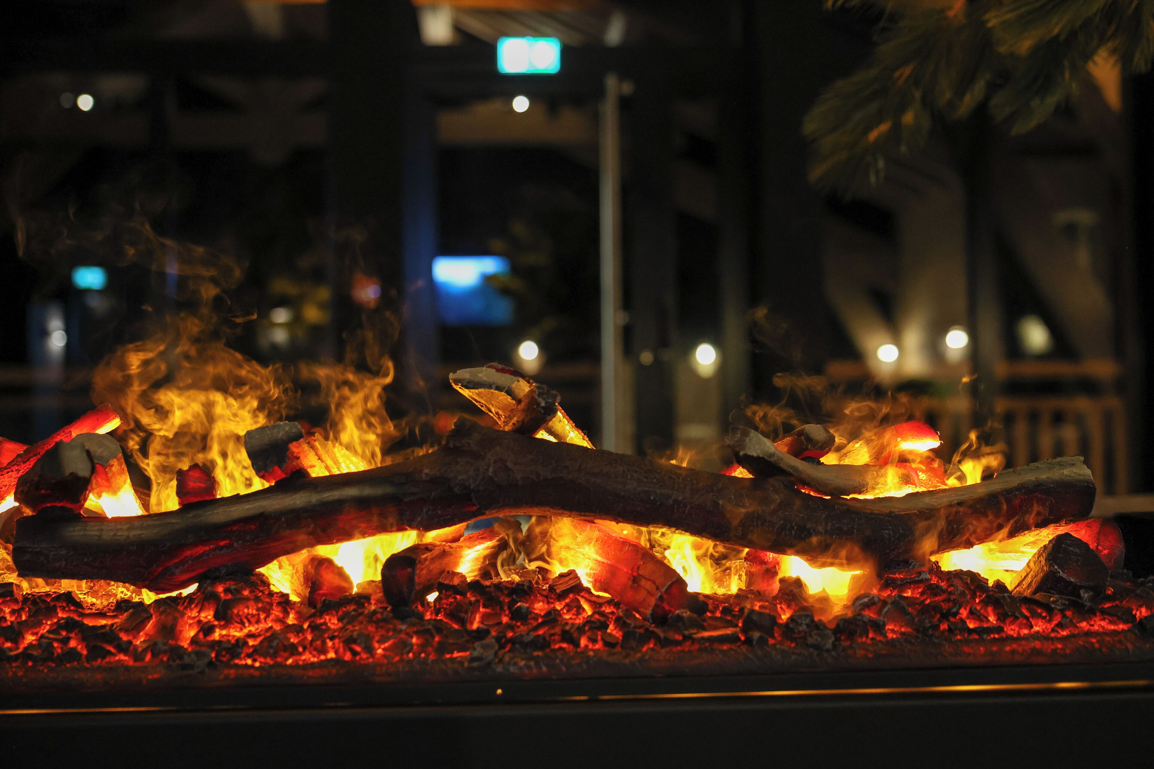 A close-up of a fire with logs and glowing embers, likely in an outdoor setting.