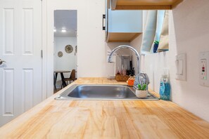 A kitchen with a wooden countertop, stainless steel sink, and a small potted plant. - Detached Casitas/Walk to UNM and Hospital/Full Kitchen/Fenced Yard/AC&Heat (Albuquerque)