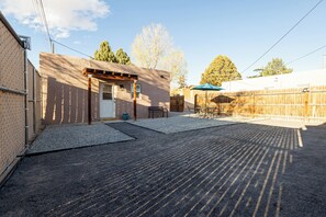 A covered outdoor area with a patio, a wooden fence, and a building with a door and windows. - Detached Casitas/Walk to UNM and Hospital/Full Kitchen/Fenced Yard/AC&Heat (Albuquerque)