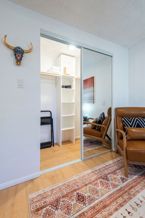 A room with a sliding closet door, a brown leather chair, a patterned rug, and a wall-mounted decorative bull skull. - Detached Casitas/Walk to UNM and Hospital/Full Kitchen/Fenced Yard/AC&Heat (Albuquerque)