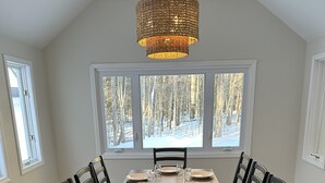A dining room with a wooden table set for six, surrounded by chairs, under a woven pendant light. - Your Wolfeboro Home Away From Home (Wolfeboro)