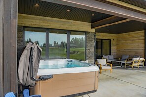 Ein Whirlpool mit Abdeckung, eine Holzterrasse und eine Sitzgelegenheit mit Stühlen und Tisch.