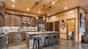 A spacious kitchen with wooden cabinets, stainless steel appliances, and a large island with bar stools.