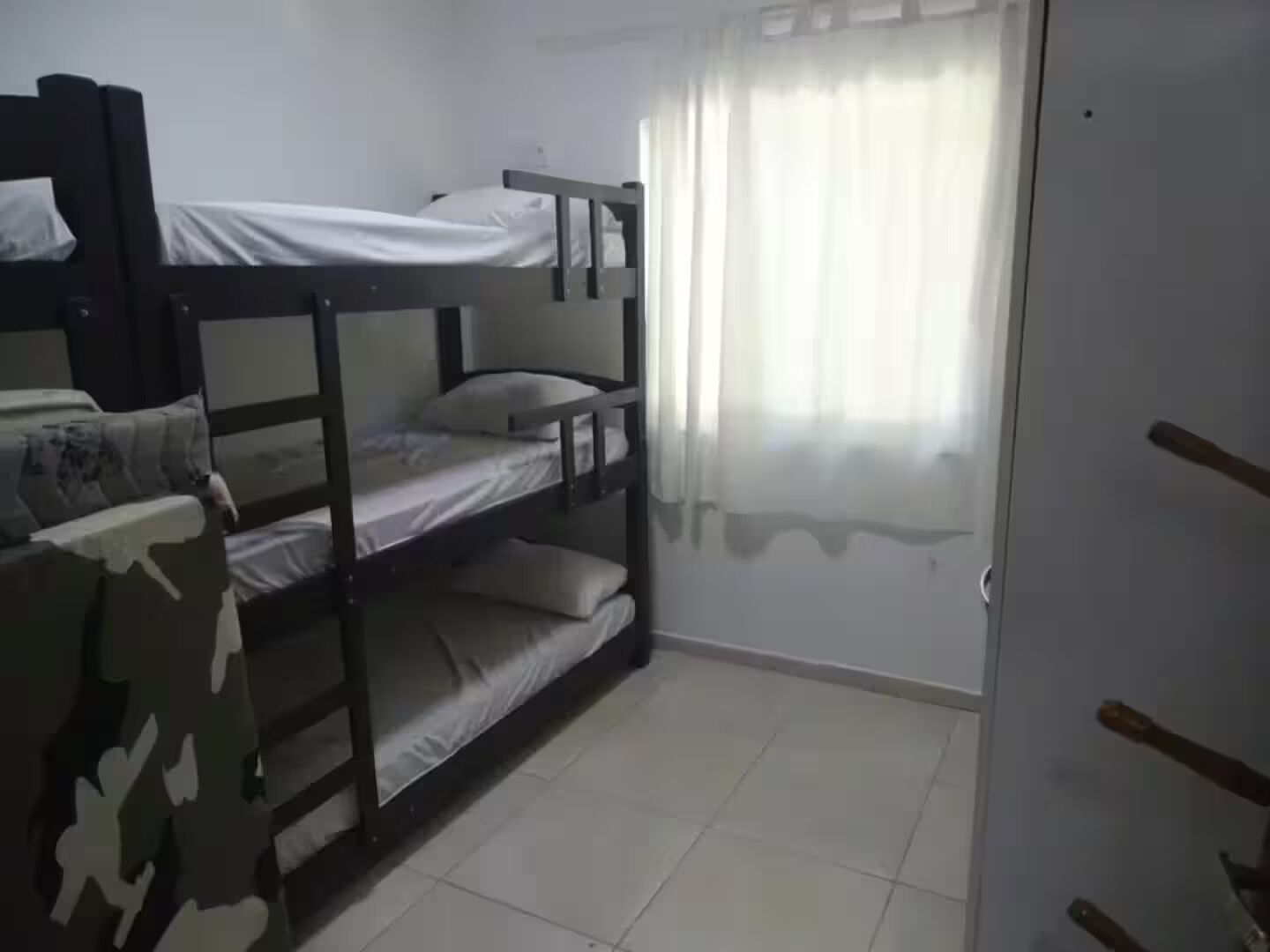 A room with bunk beds, a door, and a window with curtains.