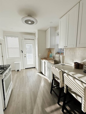 A kitchen with white cabinets, a stove, and a sink.
