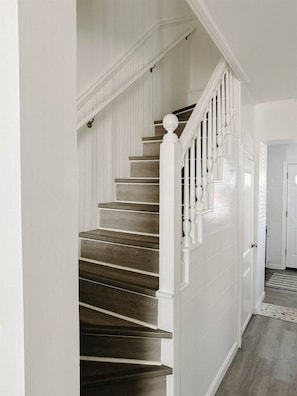 A staircase with wooden steps and white railings, leading to a door.