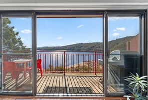 Enjoy the serene view from this outdoor deck, overlooking a body of water and distant hills.