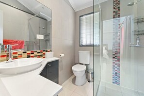 Features a large sink with a sleek, curved design and a glass-enclosed shower area with a chrome showerhead.