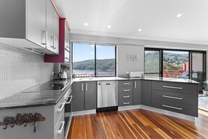 Enjoy a meal with a view from this kitchen, featuring a dishwasher, oven, and large window overlooking a scenic landscape.