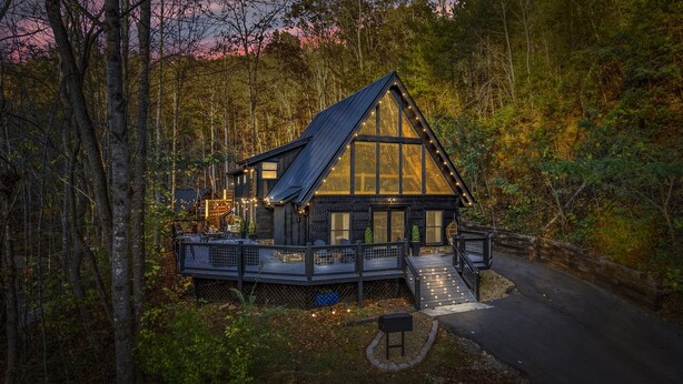 A cabin with a deck, surrounded by forest.