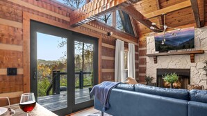 A cozy living room with a blue sofa, a fireplace, and a scenic view through the glass door.