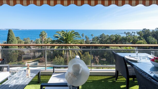 Ein Balkon mit Meerblick, ein Esstisch und eine Weinflasche.
