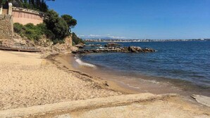 Ein Strand mit felsigem Ufer, klarem Himmel und einer entfernten Skyline.