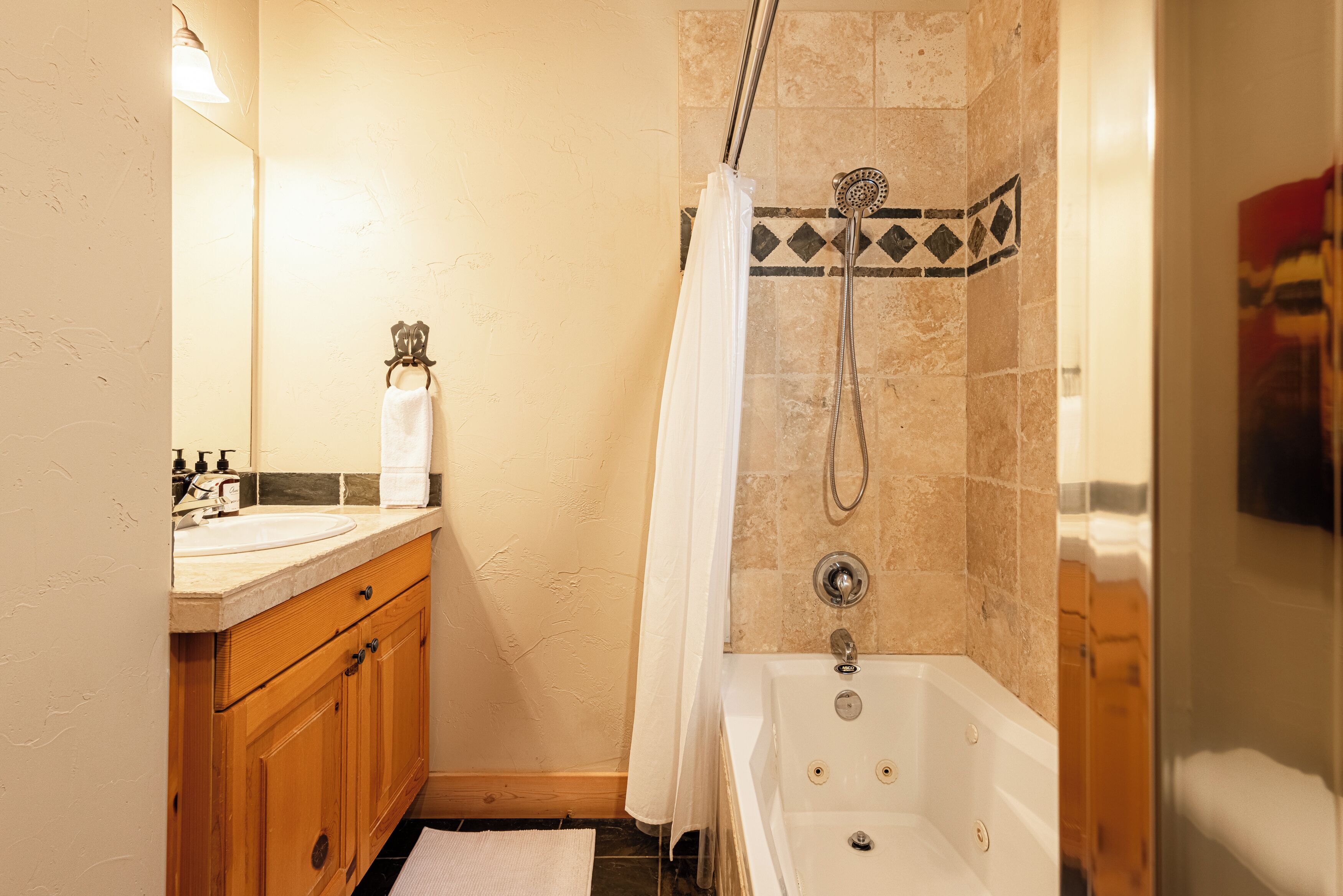 A bathroom with a bathtub, a shower, a sink, and wooden cabinets.