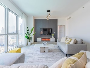 Una sala de estar moderna con chimenea, ventanas amplias y vistas a la ciudad.