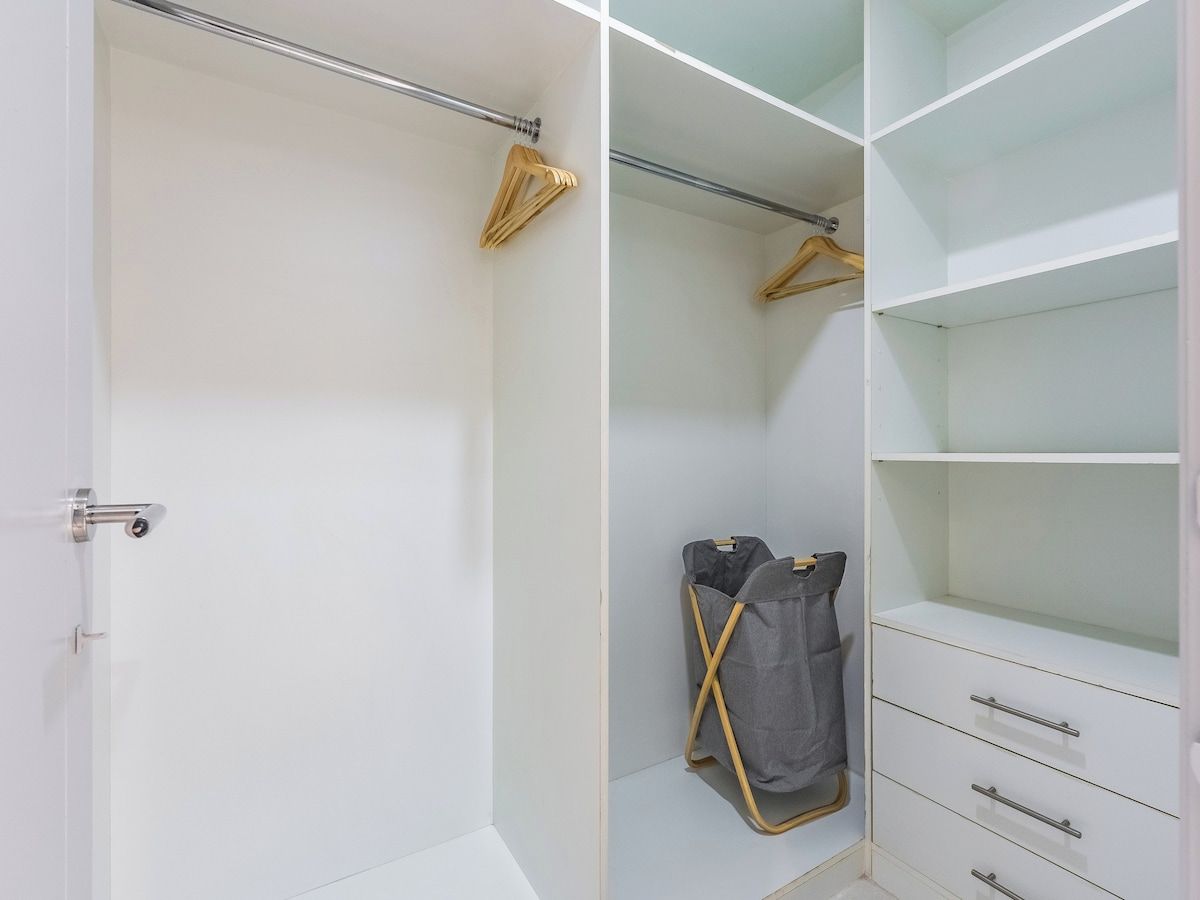 A walk-in closet with open shelving, a hanging rod, and a single drawer unit.