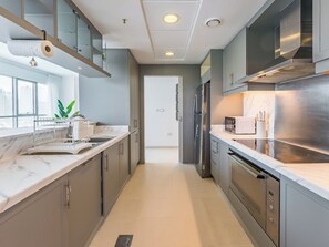 Een moderne keuken met roestvrijstalen apparatuur, marmeren aanrechtbladen en uitzicht op de stad.